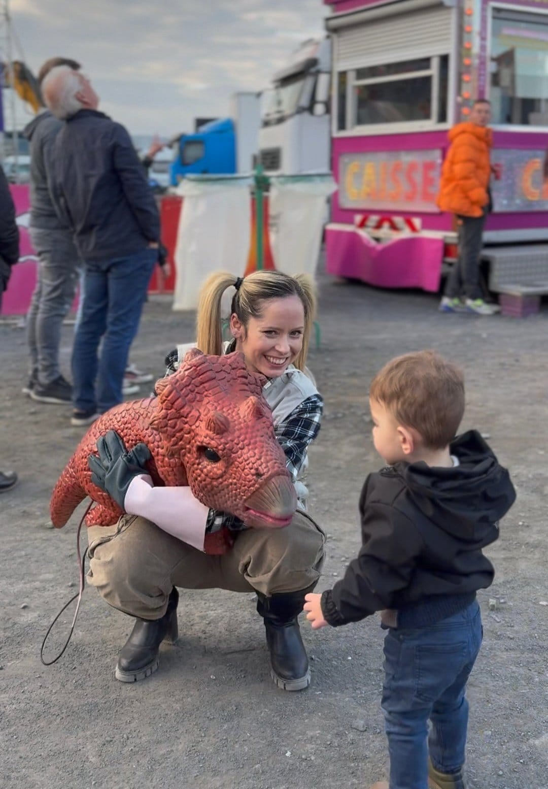 Une animatrice et son bébé dinosaure animé face à un petit garçon