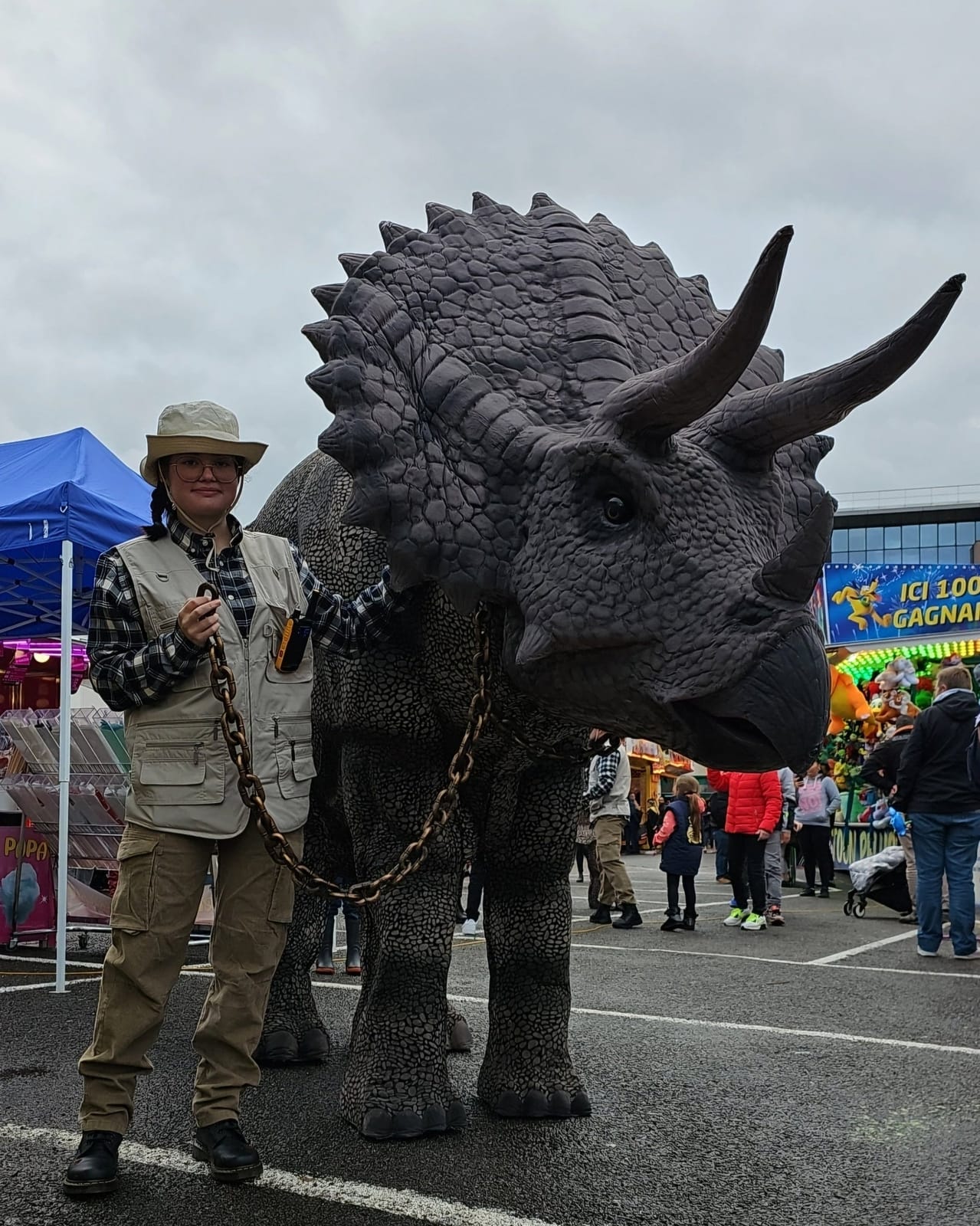 Le tricératops animé de Mascotte Dreams et son soigneur dans une fête foraine