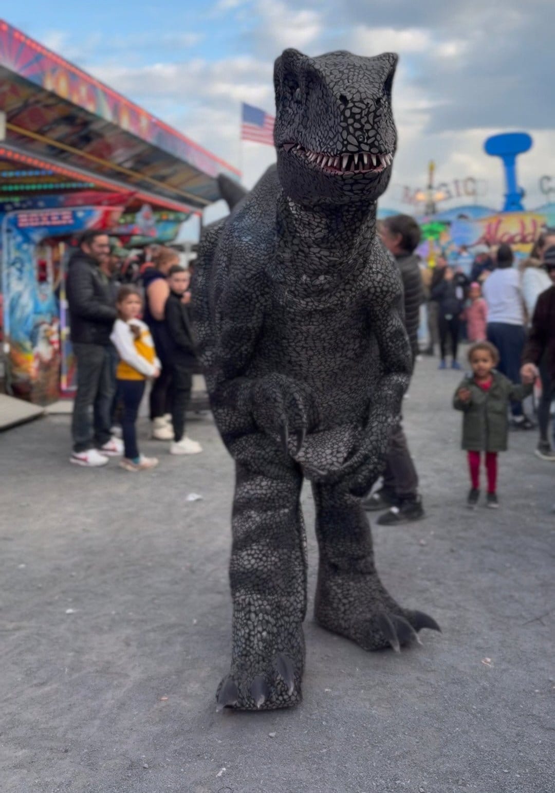 Le vélociraptor de Mascotte Dreams au milieu d'une fête foraine