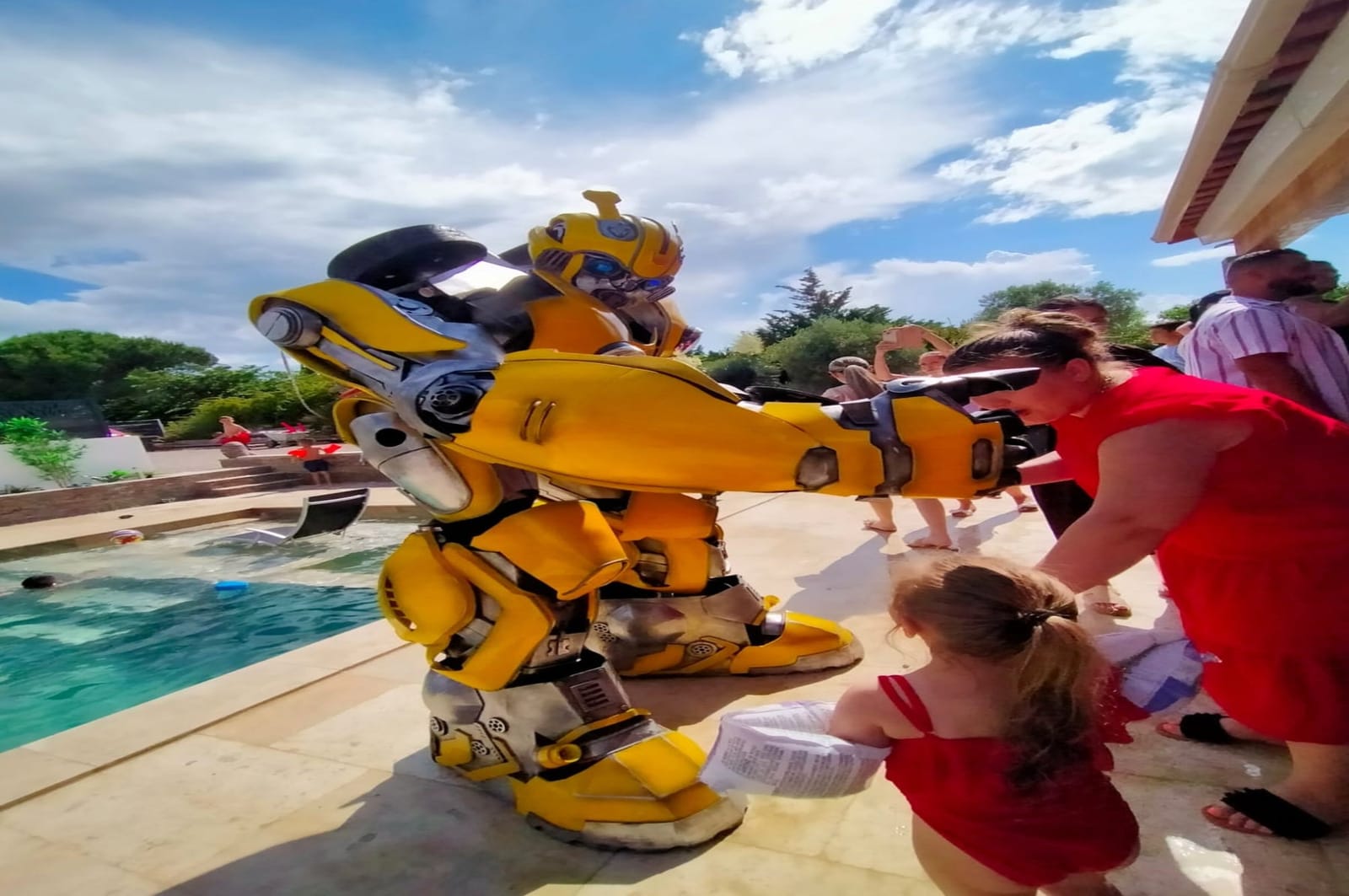 Une mascotte Mascotte Dreams au bord d'une piscine, entourée d'enfants