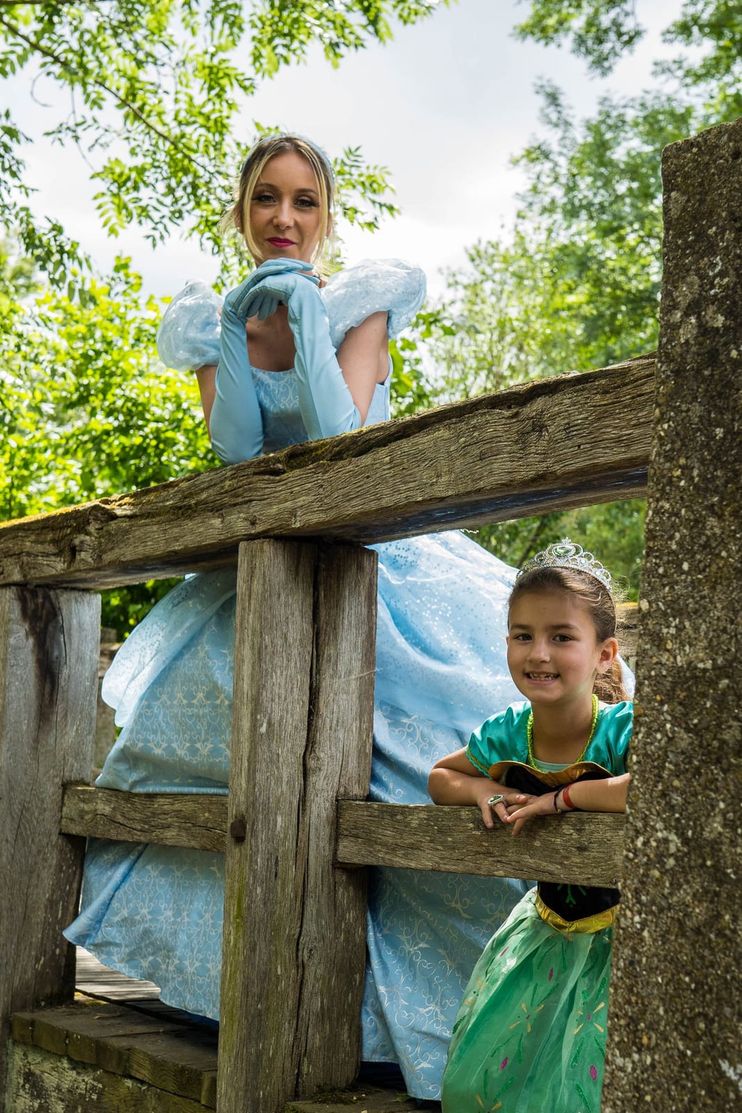 Cendrillon et une petite fille déguisée en princesse, accoudées à une barrière